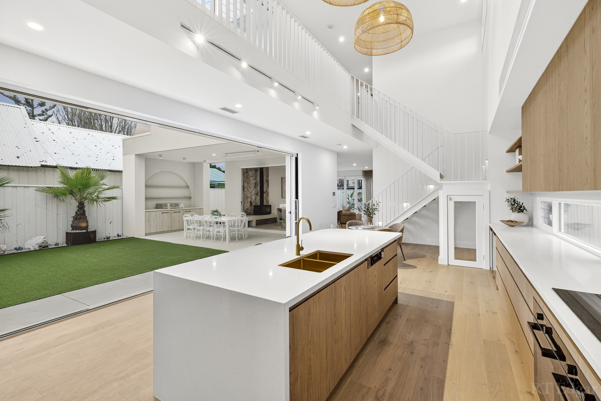 Timber and white kitchen opening directly to a green courtyard