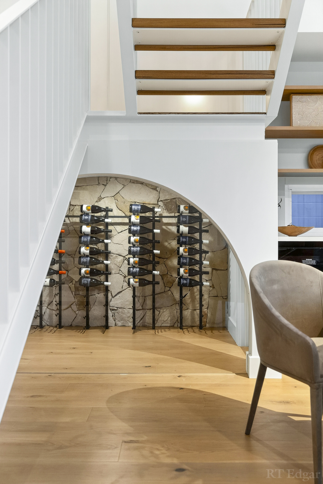 Arched stone wine cellar fitted beneath a floating timber staircase