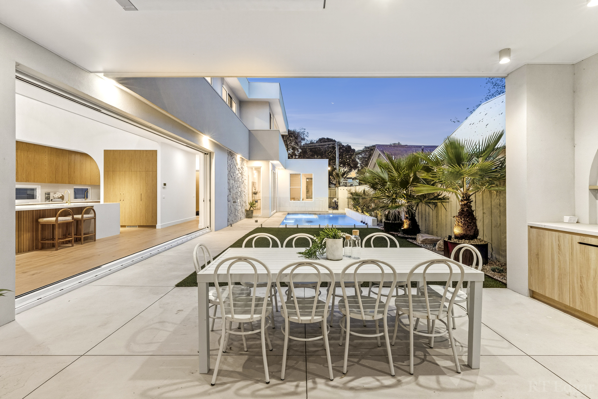 Covered courtyard dining area with an outdoor kitchen and pool beyond